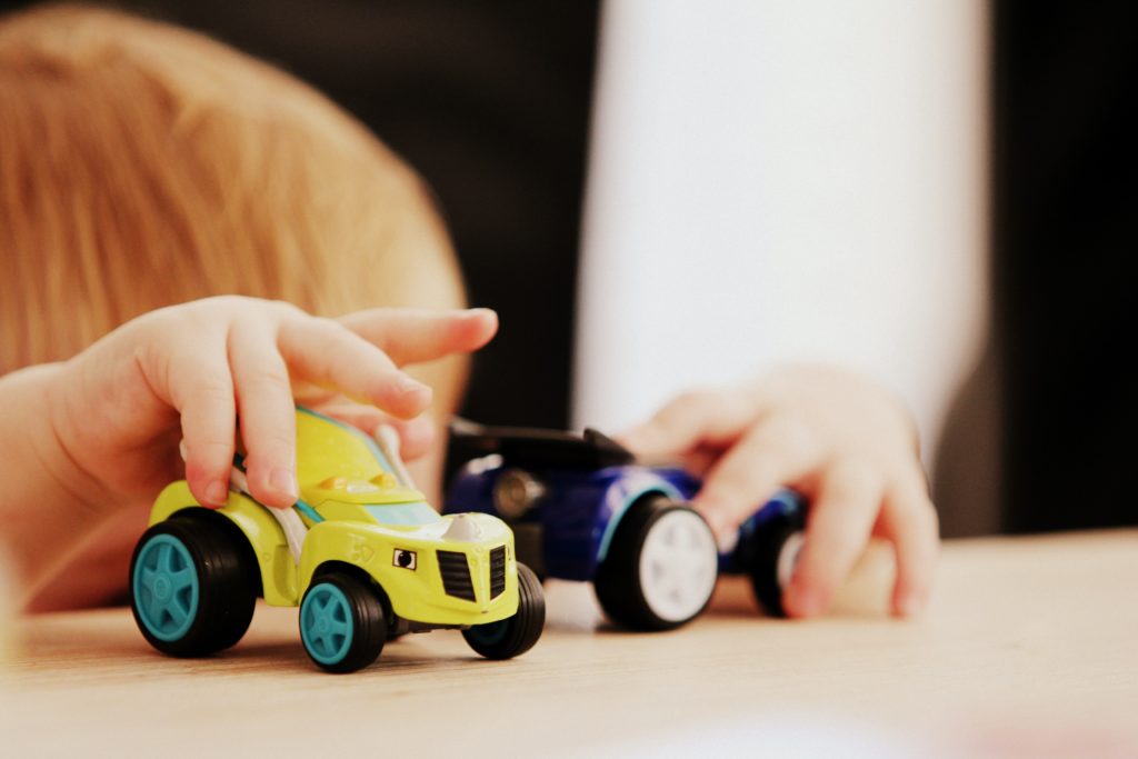 Child playing with two toy cars